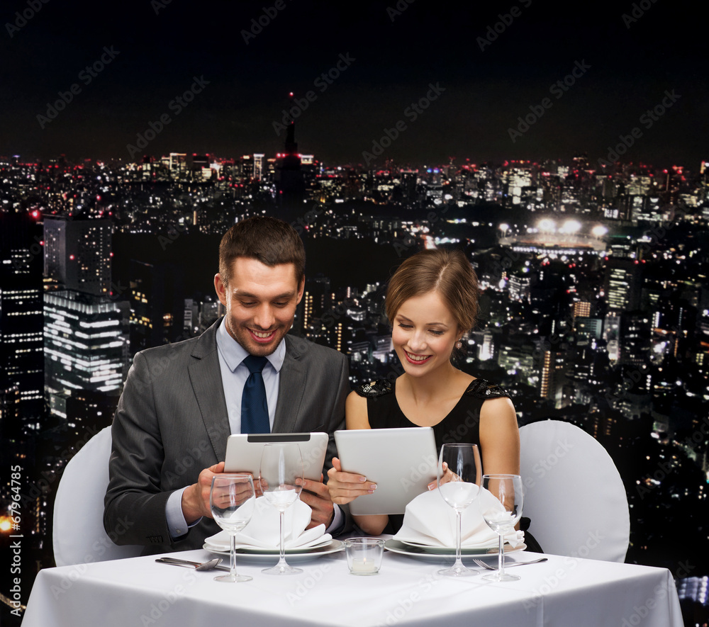 couple with menus on tablet pc at restaurant couple with menus on tablet pc at restaurant