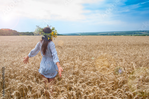 Beautiful girl in  wreath in the field of ripe wheat with lens f