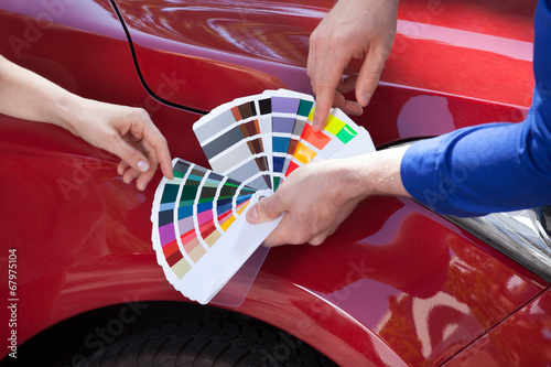 Fototapeta Naklejka Na Ścianę i Meble -  Mechanic Showing Color Samples To Customer Against Car