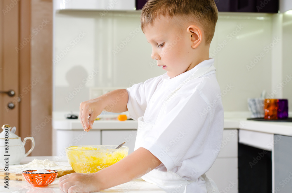 Small boy in a white apron standing baking Small boy in a white apron standing baking
