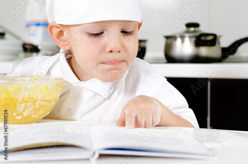 Small boy learning to cook checking his mixture