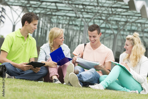 Four students learning while sitting on the ground