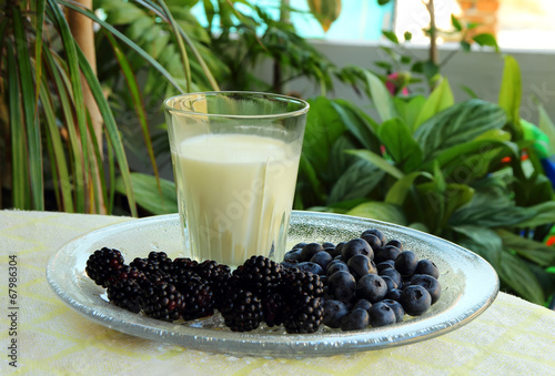 Glass of milk, blackberries and blueberries.