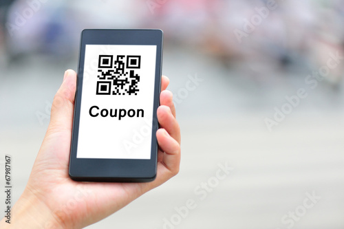 woman hand hold smart phone with coupon QR code in modern city 