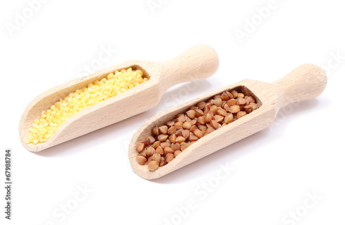 Buckwheat and millet groats on wooden spoon. White background