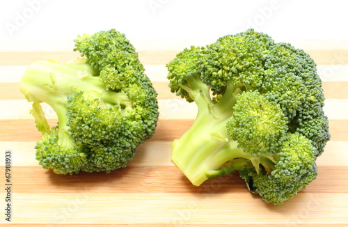 Portion of fresh green broccoli on wooden cutting board
