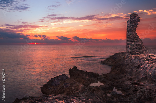 Sunset over the Sea and Rocky Coast with Ancient Ruins