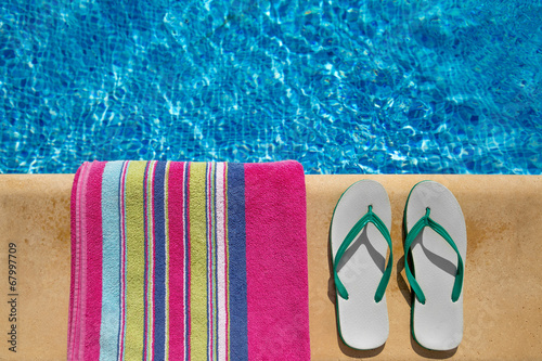 Pair of flip flop thongs and a towel on the side of a swimming