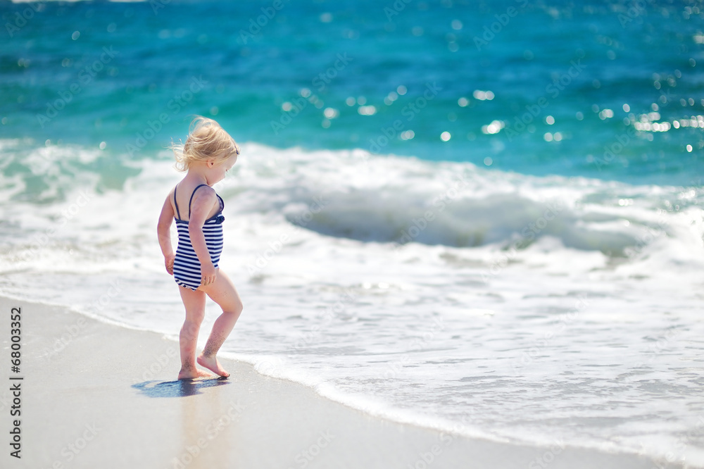 Cute little girl playing jumping over the waves