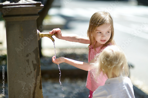 Two sisters playing with drinking water fountain