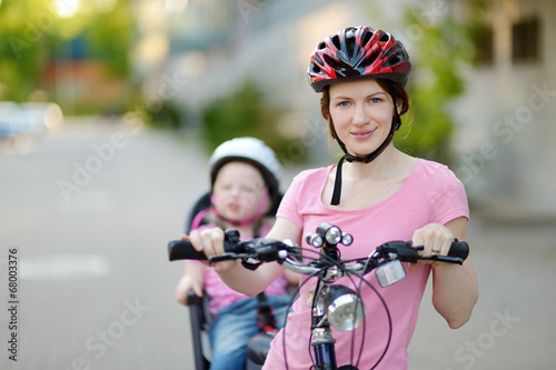 Young mother and her toddler girl riding a bicycle