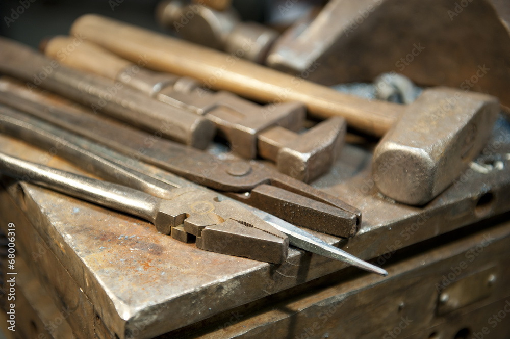 A few metal crafting tools laying next to an anvil in a metal fabrication shop. A few metal crafting tools laying next to an anvil in a metal fabrication shop.