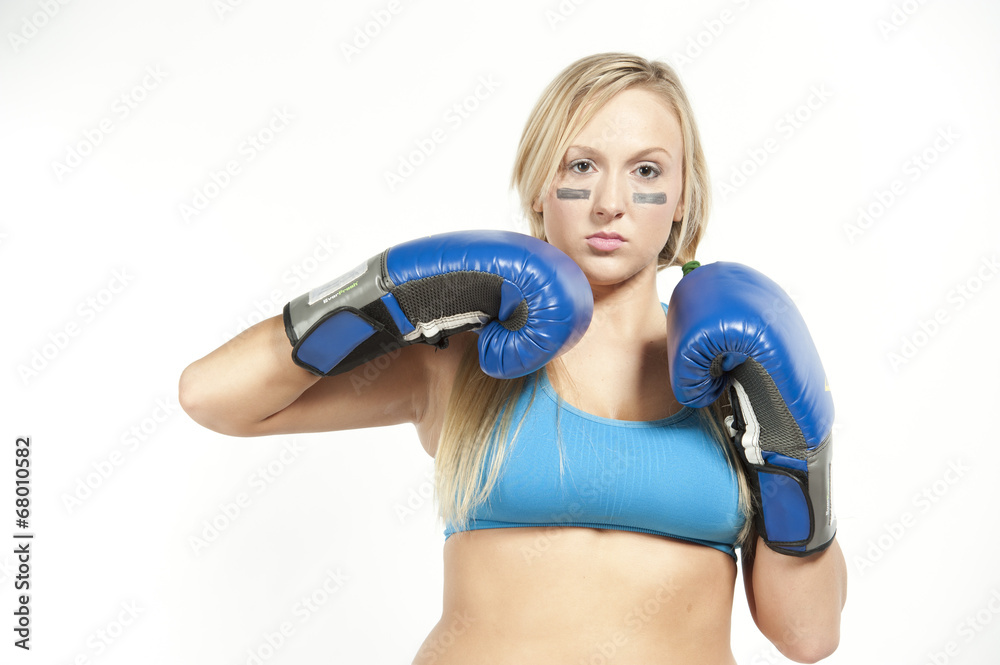 A young boxing model posing with gloves on a white background in a sportsbra.