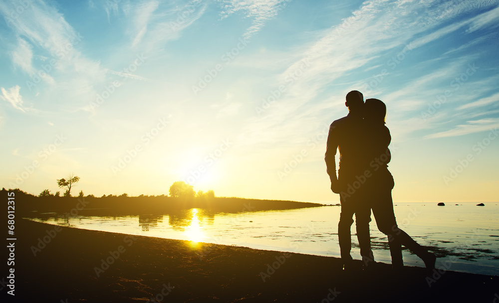 Fototapeta premium Young couple enjoying the sunset. Two silhouettes.