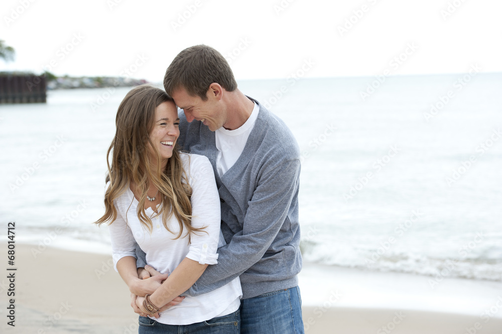 A happy young couple walking on the beach on a sunny day.