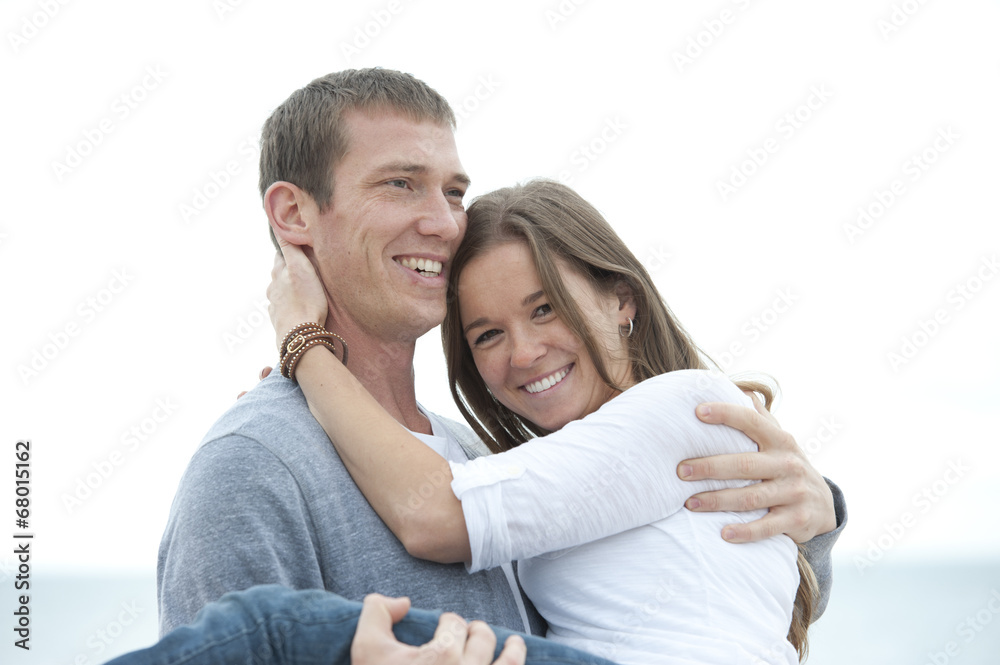 A young man carrying his wife smiling on the beach. A young man carrying his wife smiling on the beach.