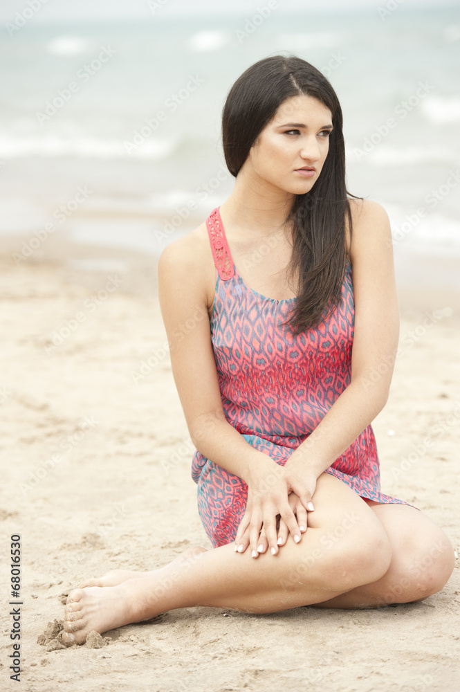 An attractive young and beautiful female model sitting at the beach on a sunny day. An attractive young and beautiful female model sitting at the beach on a sunny day.