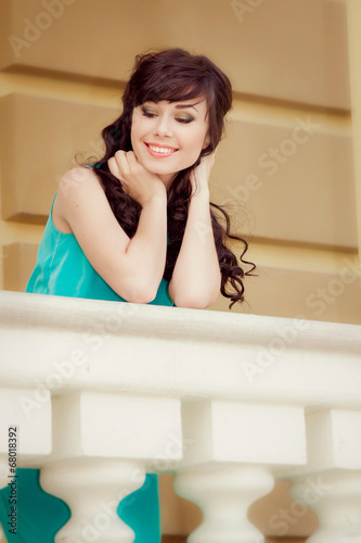 Cute cheerful brunette girl with long curly hair smiling