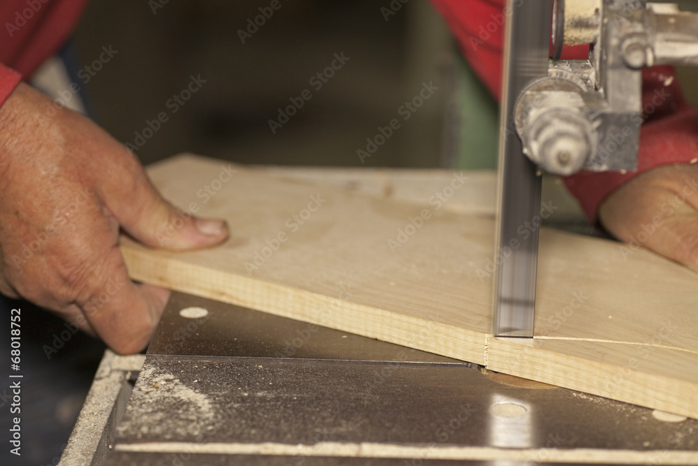 Carpenter sawing wood board on bandsaw Carpenter sawing wood board on bandsaw