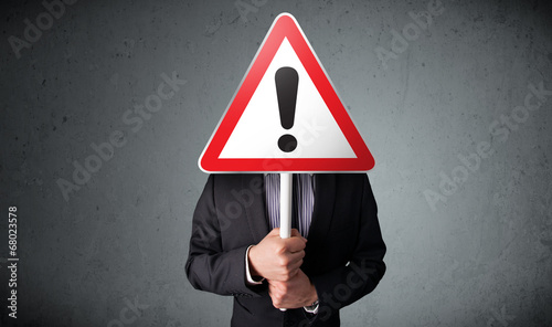 Businessman holding an exclamation road sign
