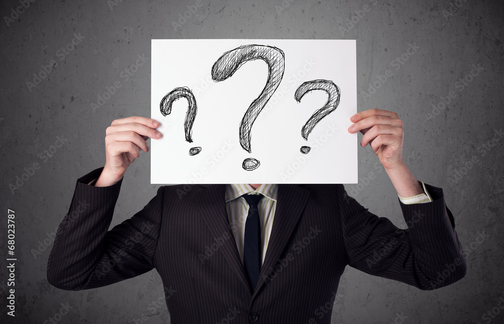 Businessman holding a paper with question marks in front of his Businessman holding a paper with question marks in front of his