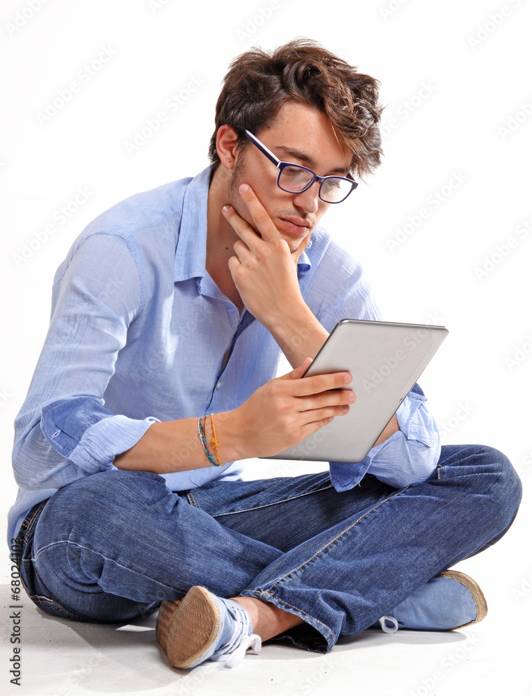 Hombre joven sentado usando un tablet digital.