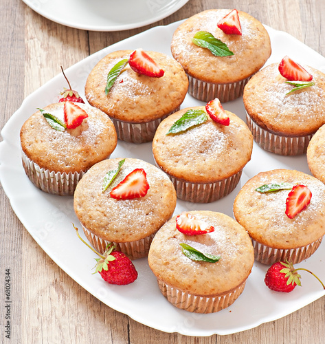 Strawberry muffin on a white plate with a fresh strawberry