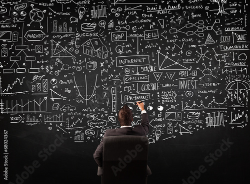 Businessman sitting in front of a blackboard with charts