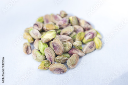 A heap of pistachio nuts on a white background on a sunny day.