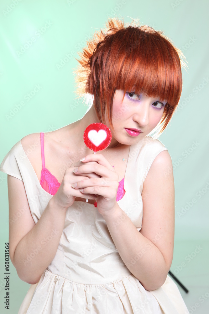 Red-haired girl with lollipop heart on blue background Red-haired girl with lollipop heart on blue background
