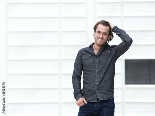 Handsome young man smiling with hand in hair