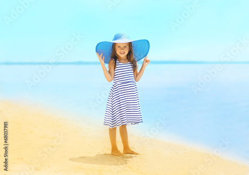 Fashion little girl in a striped dress and hat relaxing