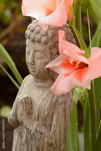 Boeddha in  bamboe tuin met bloemen photo