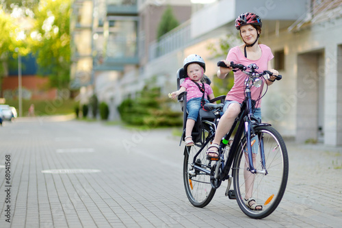 Young mother and her toddler girl riding a bicycle