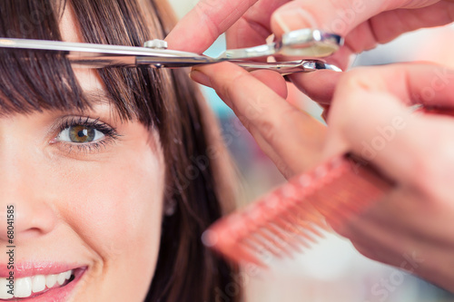 Hairdresser cutting woman bangs hair in shop photo