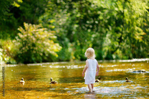 Cute toddler girl having fun by a river