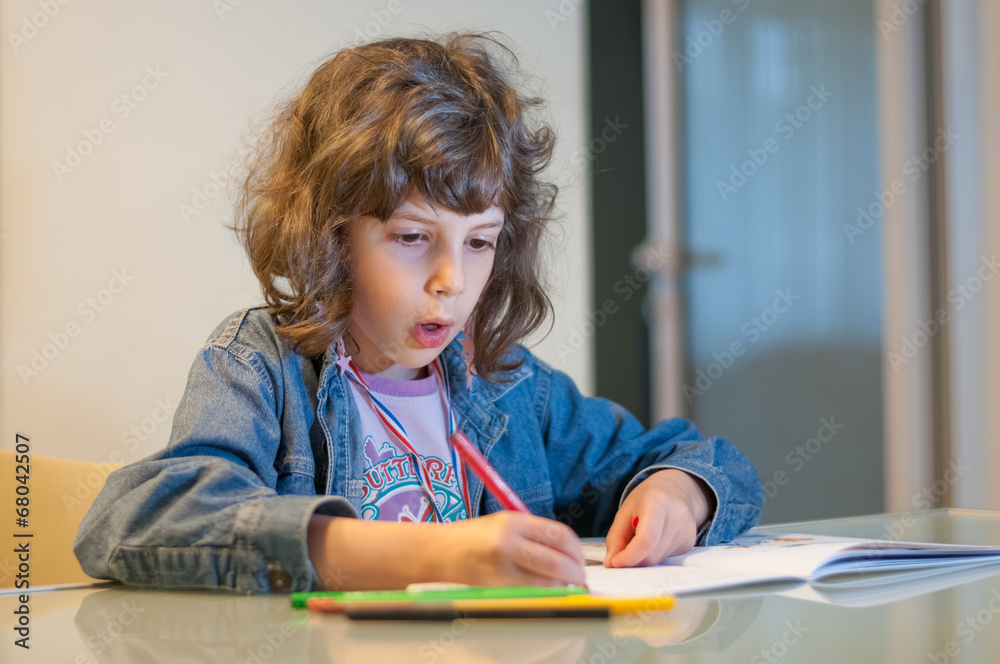 Little girl sitting at a table drawing and coloring in her book Little girl sitting at a table drawing and coloring in her book