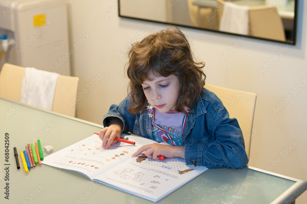 Little girl sitting at a table drawing and coloring in her book Little girl sitting at a table drawing and coloring in her book