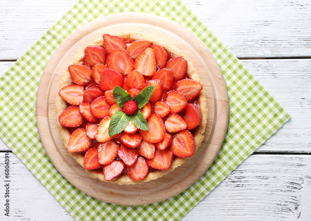 Strawberry tart on wooden tray, on color wooden background