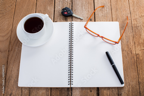 Blank nootbook wiht coffee cup and accessories on old wooden bac