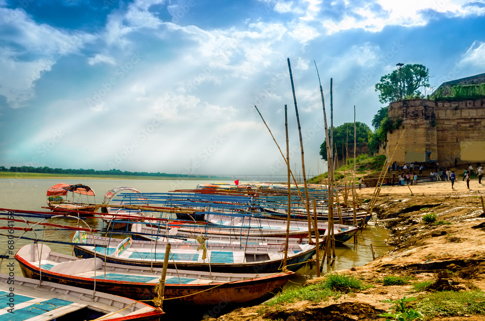big wooden boats in water with cloudy sky and sunbeams big wooden boats in water with cloudy sky and sunbeams