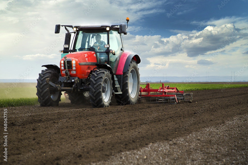 Close-up of agriculture red tractor cultivating field Close-up of agriculture red tractor cultivating field