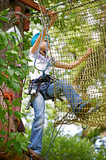 Girl is climbing on net of obstacle course