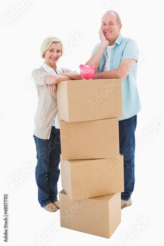 Older couple smiling at camera with moving boxes and piggy bank © WavebreakmediaMicro