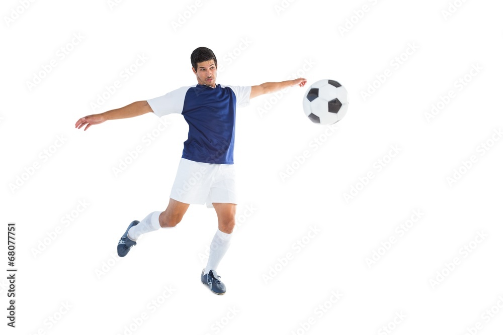 Football player in blue kicking ball