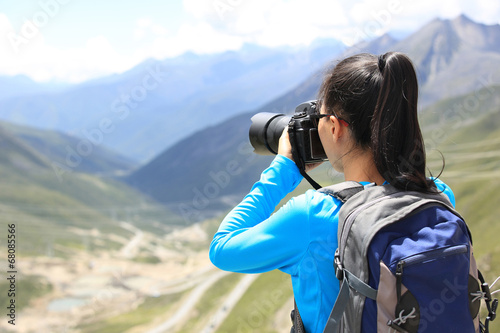 hiking woman taking photo at mountain peak in tibet,china