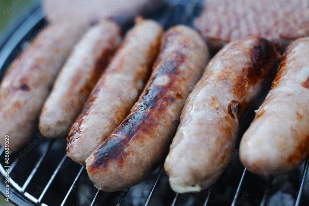 sausages and burgers cooking on barbecue