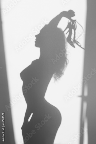 Beautiful naked woman silhouette, with sandals in hands