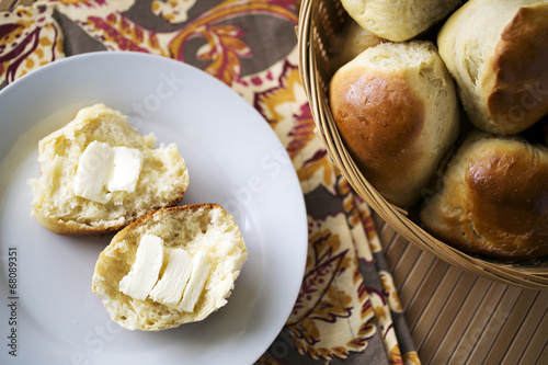 dinner rolls in basket and on white plate with butter