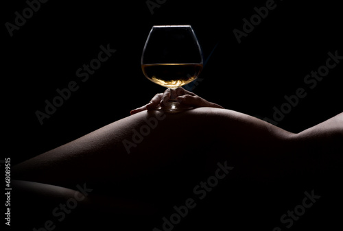 Beautiful, nude woman body silhouette and a glass of drink